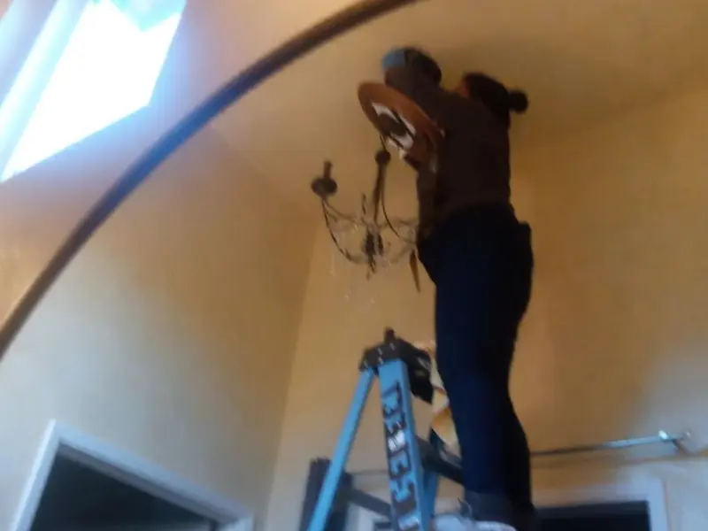 Electrician installing a chandelier in a Severn residence
